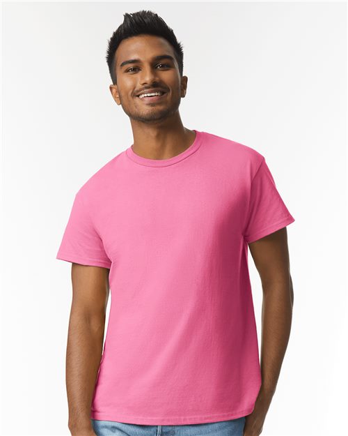 Load image into Gallery viewer, A person smiles in a vivid Gildan - Ultra Cotton® T-Shirt against a plain white backdrop. With short dark hair and arms relaxed at their sides, they effortlessly embody both comfort and style.
