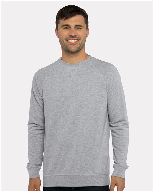 Load image into Gallery viewer, A person smiles at the camera against a white background, wearing the Next Level - Laguna Raglan Crewneck Sweatshirt, made of cotton polyester fleece, paired with dark pants.
