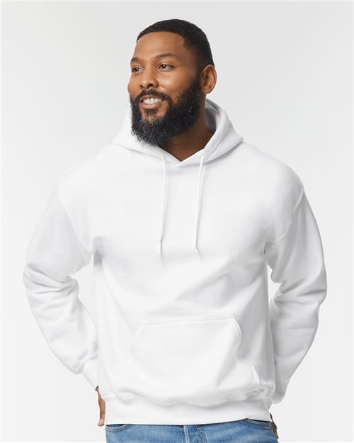 Load image into Gallery viewer, A bearded man in a Gildan DryBlend® Hooded Sweatshirt and blue jeans stands with hands in pockets, smiling slightly against a plain background.
