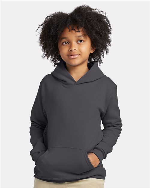 Load image into Gallery viewer, A young child with curly hair stands against a plain background, wearing a Hanes Ecosmart® Youth Hooded Sweatshirt in dark gray. Made from a cotton/polyester blend, the hoodie features a front pocket. The child&#39;s calm expression complements their light-colored pants.
