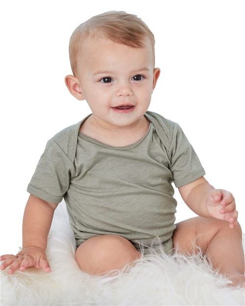 A cheerful baby with short, light brown hair sits on a fluffy white surface, smiling and looking slightly to the side while wearing a light gray BELLA + CANVAS Infant Jersey One Piece, made from Airlume cotton.