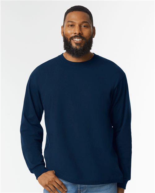 Load image into Gallery viewer, A bearded person smiles while wearing a Gildan - Hammer™ Long Sleeve T-Shirt in navy blue, made from ring-spun cotton, paired with jeans. They stand against a plain white background.
