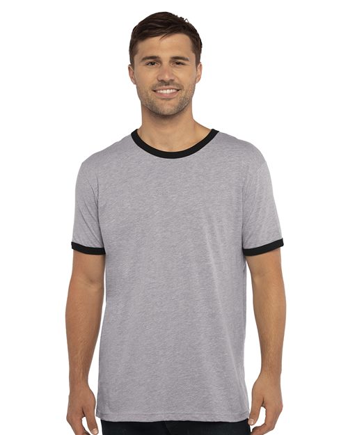 A man smiles in a Next Level Cotton Ringer T-Shirt, featuring gray fabric with black trim from the brand Next Level, made of combed ring-spun cotton. He stands against a white background, showcasing socially conscious elegance in manufacturing.