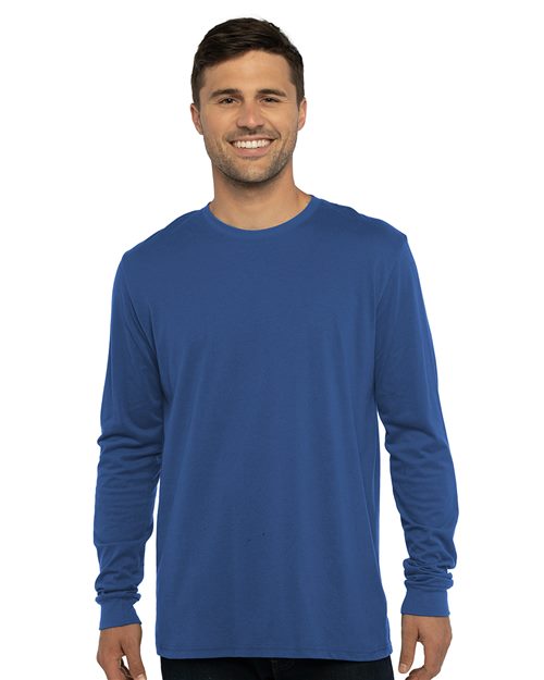 A man smiles against a white background wearing Next Level's blue Sueded Long Sleeve T-Shirt, responsibly made, paired with dark pants.