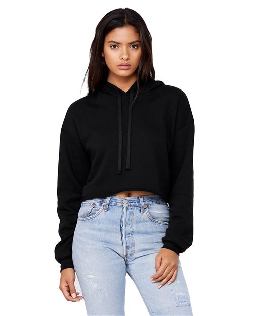 Load image into Gallery viewer, Wearing a BELLA + CANVAS Women&#39;s Crop Fleece Hoodie in black, paired with light blue distressed jeans, the person stands against a plain background. The ensemble, along with long dark hair, exudes a casually chic vibe.
