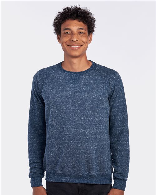 A person with curly hair smiles while wearing a JERZEES Snow Heather French Terry Crewneck Sweatshirt, standing against a plain white background.