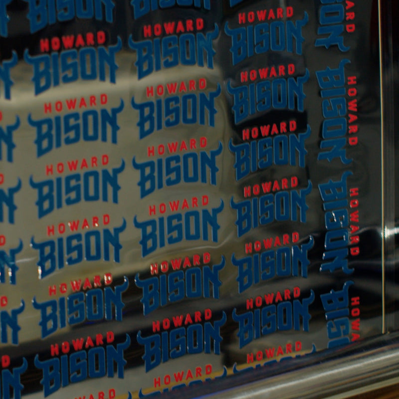 Load image into Gallery viewer, The FOREVERFILM™ 3D UV DTF TRANSFERS by Quick Transfers showcases striking blue and red &quot;Howard Bison&quot; text, with bold blue &quot;Bison&quot; contrasting against the red &quot;Howard,&quot; all set on a reflective surface for lasting vibrancy.
