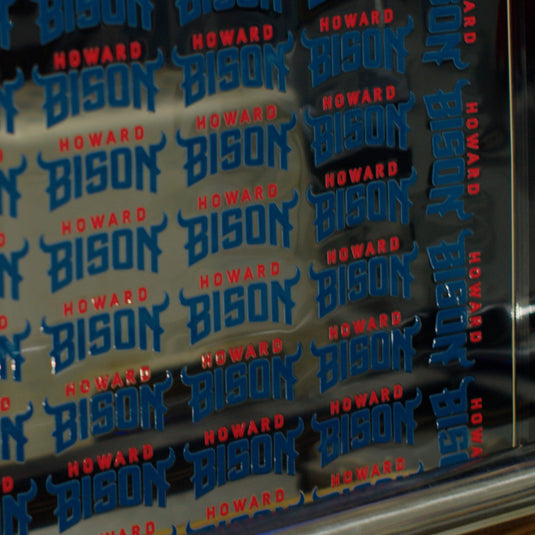 The FOREVERFILM™ 3D UV DTF TRANSFERS by Quick Transfers showcases striking blue and red "Howard Bison" text, with bold blue "Bison" contrasting against the red "Howard," all set on a reflective surface for lasting vibrancy.