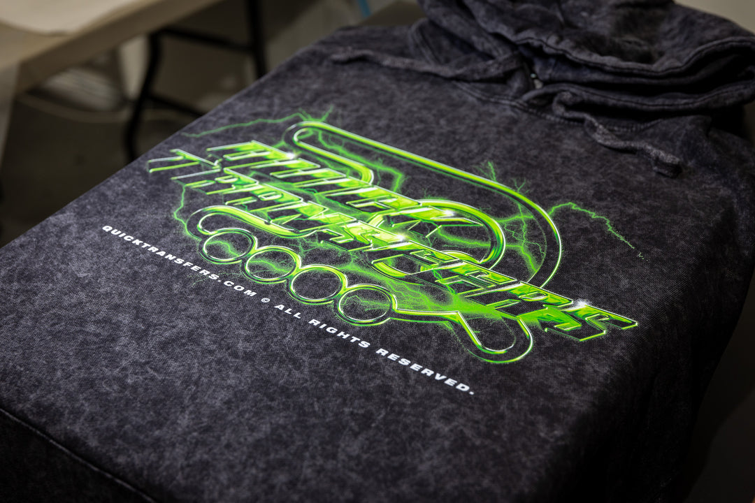 A black hoodie features a dynamic green design with a stylized lightning bolt and the words "Quick Transfers." Below that, it reads "quicktransfers.com All Rights Reserved." Crafted with FASTFILM™ DTF TRANSFERS - Build a Gang Sheet by Quick Transfers, this hoodie has a slightly textured look for added style.