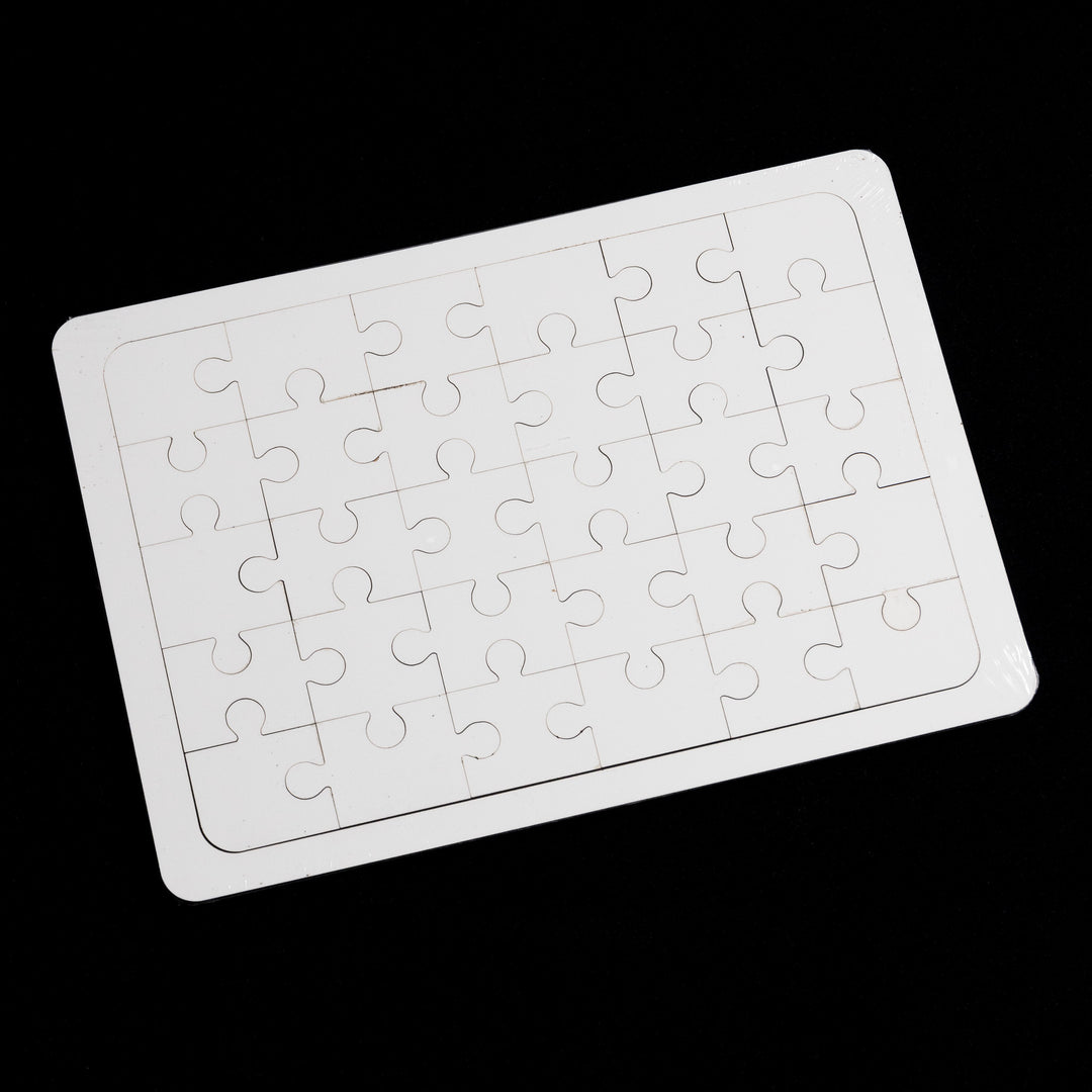 The Quick Transfers Blank Sublimation Puzzle (5x7") with 35 blank white pieces is elegantly displayed on a rectangular board against a black background, showcasing the simplicity and personal touch of its uniform design.