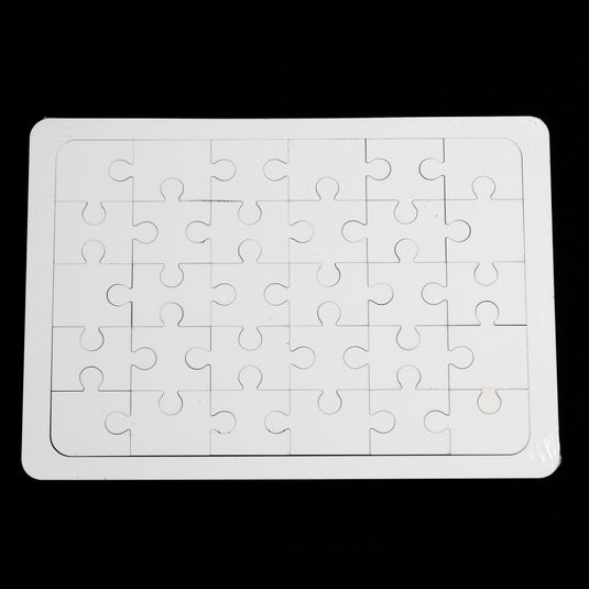 A 7x10" white rectangular Blank Sublimation Puzzle by Quick Transfers, featuring four rows of six interlocking pieces, rests on a black surface, ready for personalization.