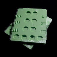 Green plastic panels with circular cutouts and hinges resemble a Quick Transfers Shirt Folder against a black background.