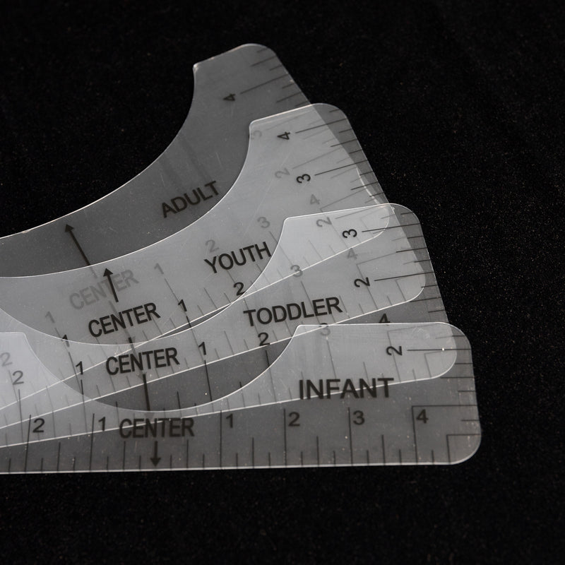 Load image into Gallery viewer, The Quick Transfers Alignment Ruler set includes four transparent rulers labeled &quot;Infant,&quot; &quot;Toddler,&quot; &quot;Youth,&quot; and &quot;Adult&quot; for professional-quality apparel decoration, all arranged in a fan shape on a dark background for effortless crafting precision.
