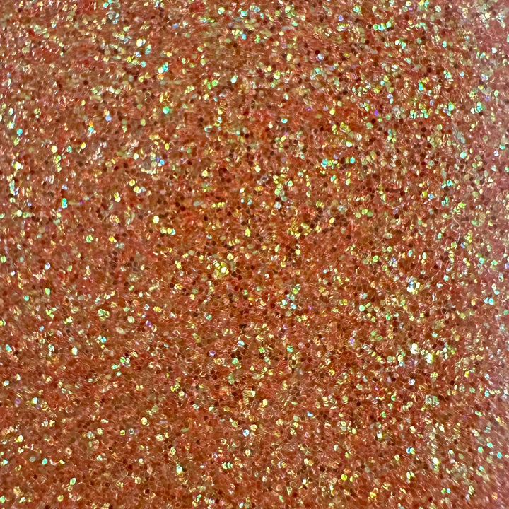 Close-up of copper EconoGlitter Vinyl by Quick Transfers scattered densely, reflecting light for a sparkling effect with pink and gold hints. The textured surface appears vibrant, showcasing the durable Glitter Heat Transfer Vinyl's lively and dynamic visual.